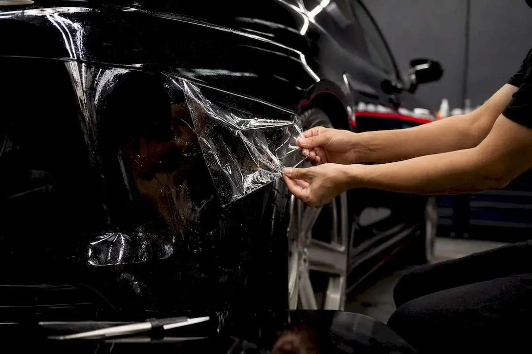 Hands peeling paint protection film at low angle