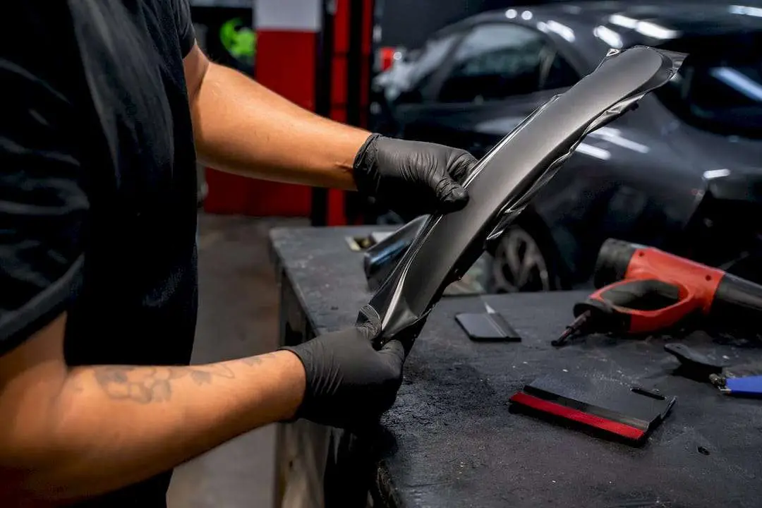 Hands applying matte vinyl wrap to car trim