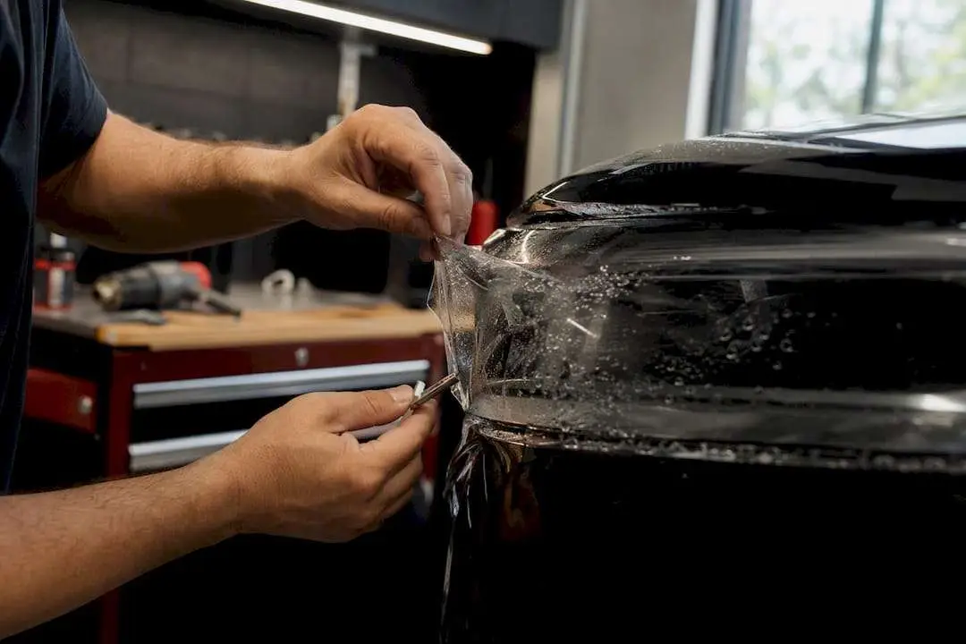 Technician applying clear PPF on headlight close-up