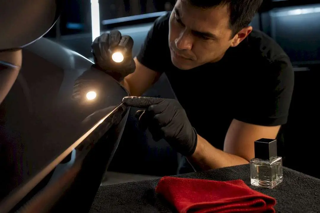 Technician inspecting a partially coated vehicle panel